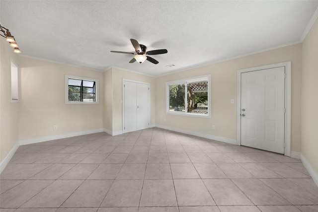 unfurnished room featuring a textured ceiling, ceiling fan, ornamental molding, and baseboards