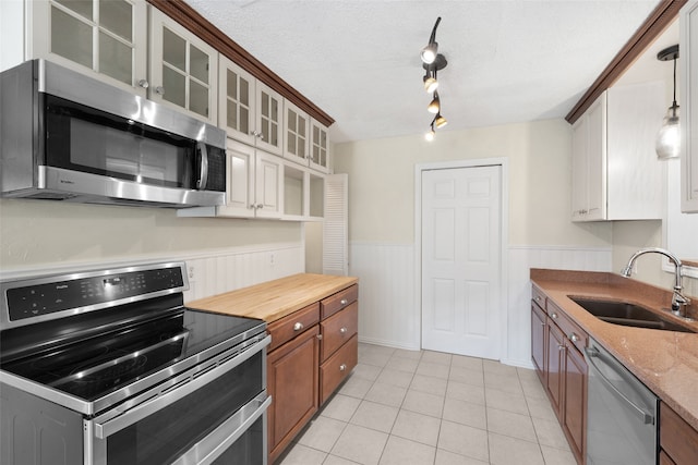 kitchen featuring stainless steel appliances, a textured ceiling, sink, light tile patterned floors, and white cabinetry