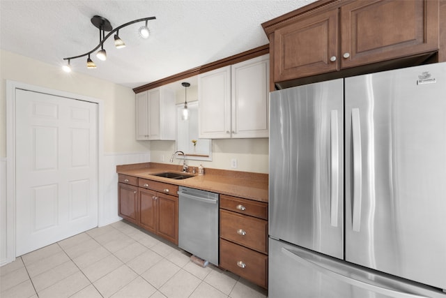 kitchen featuring a textured ceiling, sink, light tile patterned flooring, and stainless steel appliances