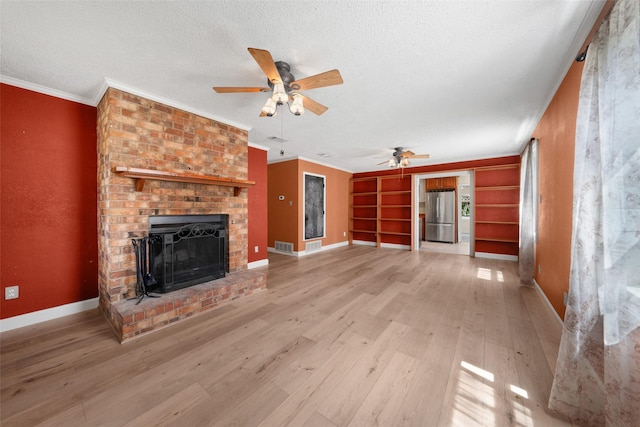 unfurnished living room featuring a textured ceiling, light wood-style flooring, a fireplace, baseboards, and crown molding