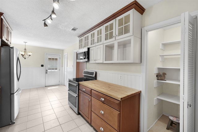 kitchen with white cabinets, appliances with stainless steel finishes, a notable chandelier, and a textured ceiling