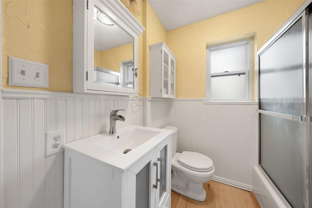 full bathroom featuring toilet, a wainscoted wall, wood finished floors, and vanity