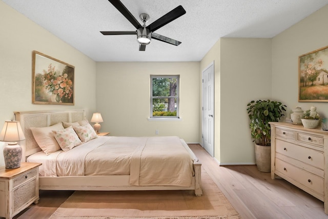 bedroom featuring a textured ceiling, light wood-type flooring, a ceiling fan, and baseboards