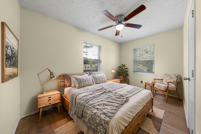 bedroom with a textured ceiling, a ceiling fan, and wood finished floors