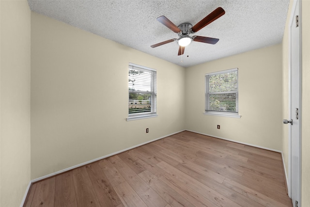 empty room featuring ceiling fan, a textured ceiling, baseboards, and wood finished floors