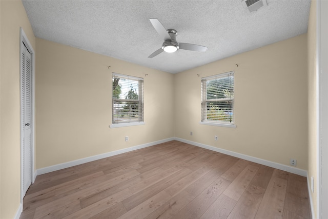 unfurnished bedroom featuring a textured ceiling, light hardwood / wood-style floors, ceiling fan, and a closet