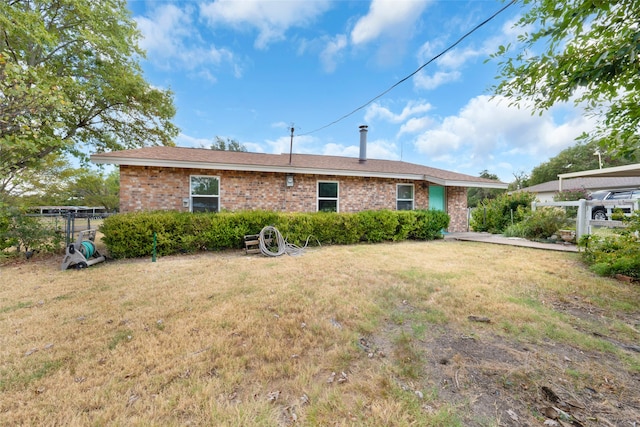 back of property featuring brick siding, fence, and a yard