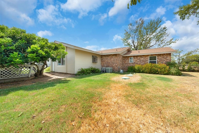 rear view of property featuring brick siding, a lawn, and central air condition unit