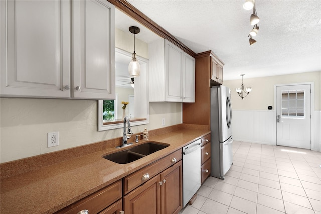 kitchen featuring a sink, pendant lighting, dishwasher, and freestanding refrigerator