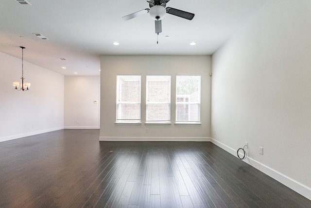 empty room with ceiling fan with notable chandelier and dark hardwood / wood-style flooring