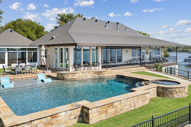 view of swimming pool featuring a water view, an in ground hot tub, a patio area, and a lawn