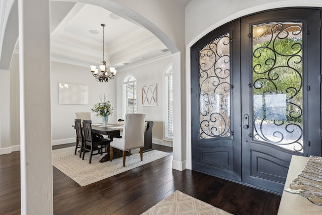 foyer entrance with a notable chandelier, a tray ceiling, dark wood-type flooring, and french doors