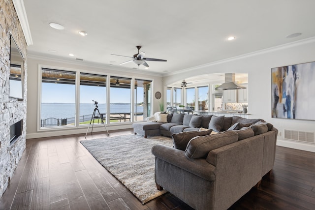 living room featuring a water view, ornamental molding, dark wood-type flooring, and a fireplace