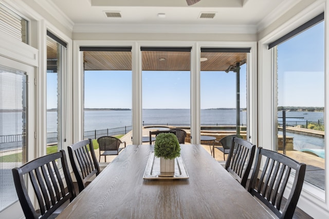 dining area with crown molding, plenty of natural light, and a water view