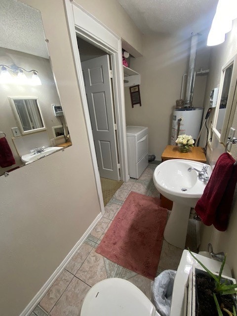 bathroom featuring a textured ceiling, gas water heater, separate washer and dryer, and tile patterned floors