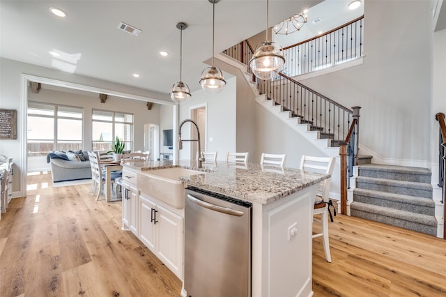 kitchen with light wood-style floors, white cabinetry, a sink, and stainless steel dishwasher