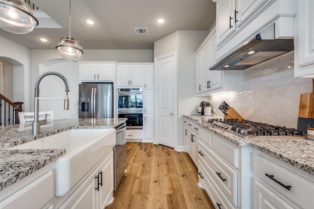 kitchen featuring light wood-style floors, appliances with stainless steel finishes, under cabinet range hood, white cabinetry, and a sink