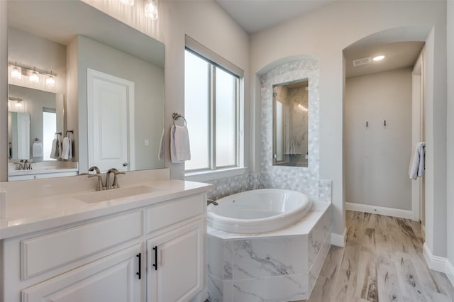 full bath with baseboards, visible vents, wood finished floors, vanity, and a bath