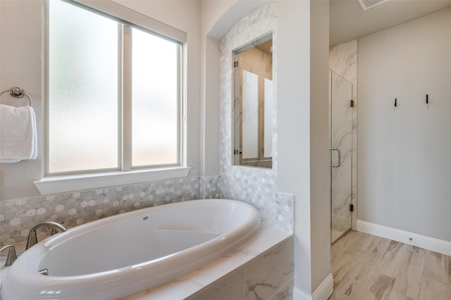 full bath with wood finished floors, baseboards, a marble finish shower, and a bath