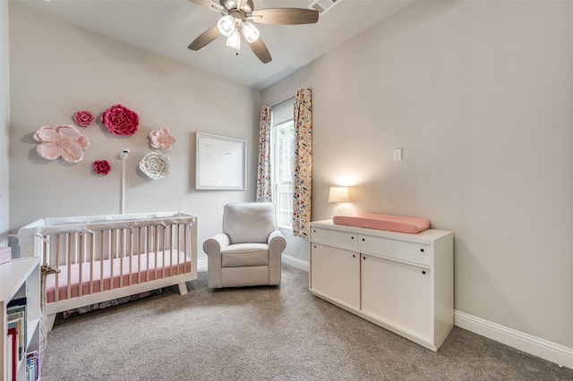 bedroom featuring a nursery area, ceiling fan, baseboards, and light colored carpet