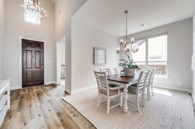 dining room featuring an inviting chandelier, baseboards, visible vents, and light wood finished floors