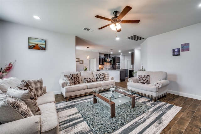 living room with a ceiling fan, dark wood finished floors, visible vents, and baseboards