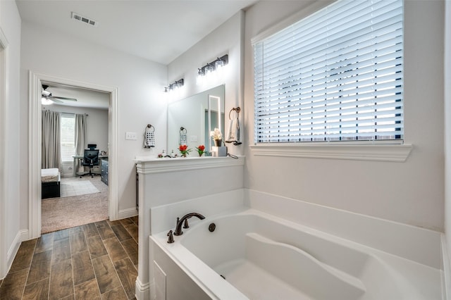 bathroom featuring visible vents, wood tiled floor, connected bathroom, baseboards, and a bath