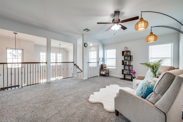 carpeted living room with a healthy amount of sunlight and ceiling fan with notable chandelier