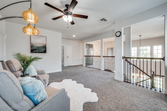 carpeted living area with baseboards, visible vents, and a ceiling fan