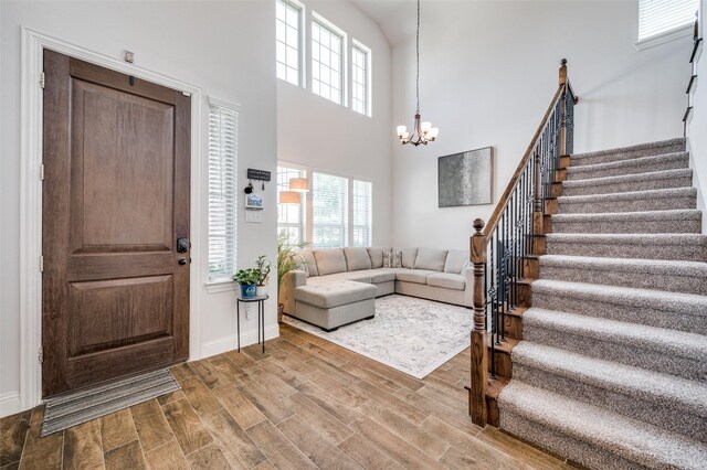 foyer entrance with light hardwood / wood-style flooring, a chandelier, and a high ceiling