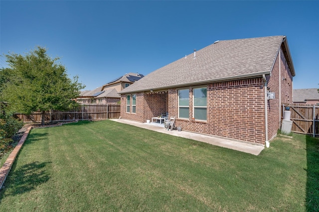 rear view of house featuring a yard, brick siding, a patio, and a fenced backyard