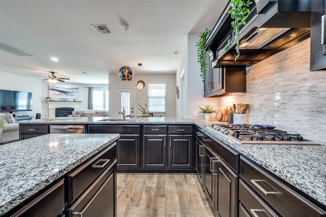 kitchen featuring pendant lighting, stainless steel appliances, light stone counters, and light wood-type flooring