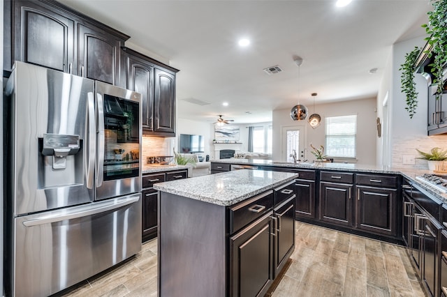 kitchen with hanging light fixtures, kitchen peninsula, stainless steel fridge, and tasteful backsplash