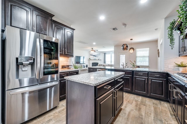 kitchen with appliances with stainless steel finishes, visible vents, a peninsula, and tasteful backsplash