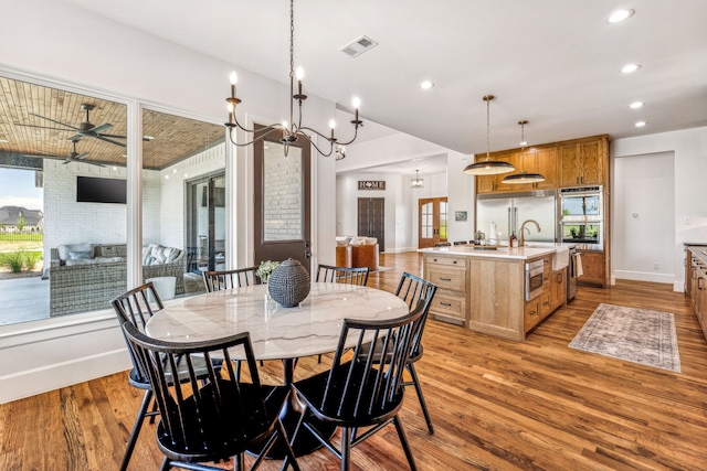 dining space with wood-type flooring, an inviting chandelier, and plenty of natural light