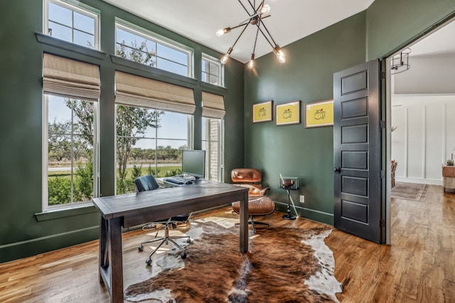 office space with hardwood / wood-style flooring, a healthy amount of sunlight, and a notable chandelier