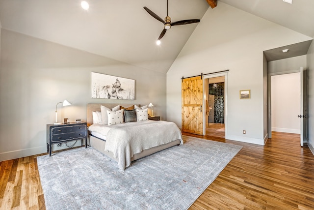 bedroom with high vaulted ceiling, ceiling fan, a barn door, beamed ceiling, and wood-type flooring