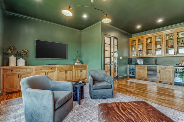 living room featuring wine cooler, ornamental molding, indoor bar, and light wood-type flooring