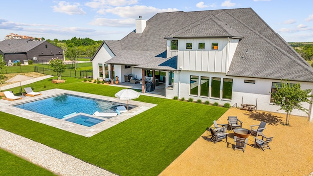 back of house with a swimming pool with hot tub, a patio area, and a yard