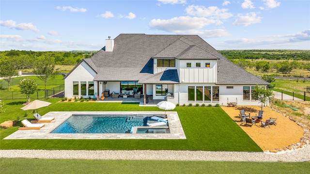 rear view of house with an outdoor hangout area, a balcony, a swimming pool with hot tub, a patio, and a lawn