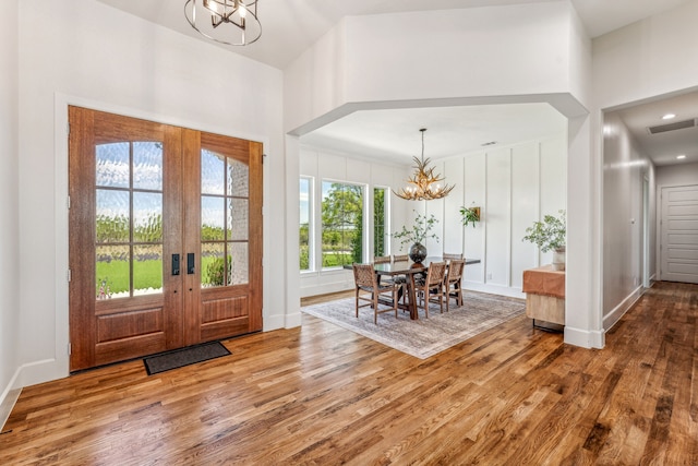 foyer entrance featuring plenty of natural light, light hardwood / wood-style flooring, french doors, and a notable chandelier