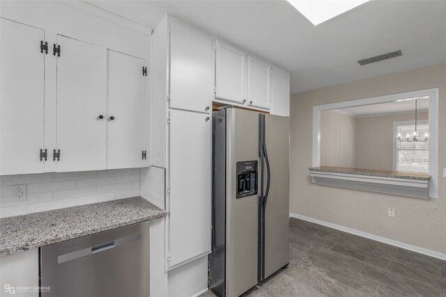 kitchen with appliances with stainless steel finishes, tasteful backsplash, a chandelier, light stone counters, and white cabinets