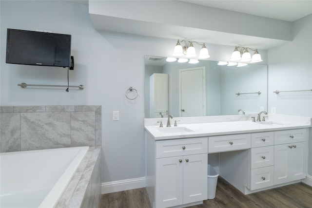 bathroom featuring hardwood / wood-style floors, a relaxing tiled tub, and vanity