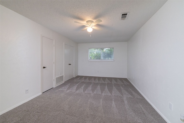 spare room with a textured ceiling, carpet, and ceiling fan