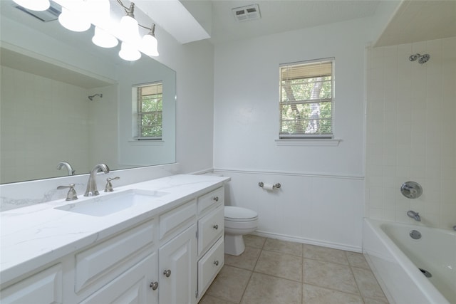 full bathroom featuring tiled shower / bath combo, vanity, toilet, and a healthy amount of sunlight