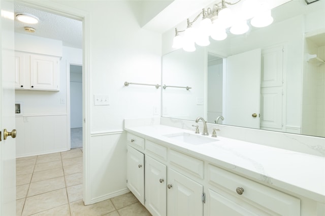 bathroom with a textured ceiling, vanity, and tile patterned floors