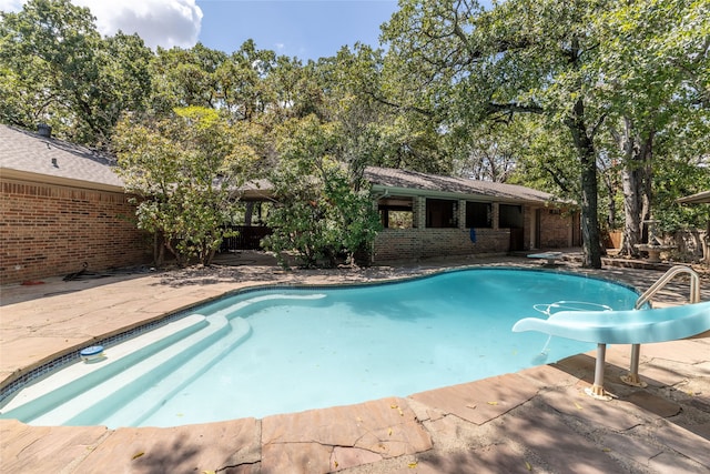 view of pool featuring a water slide and a patio