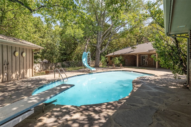 view of pool featuring a water slide, a diving board, and a patio