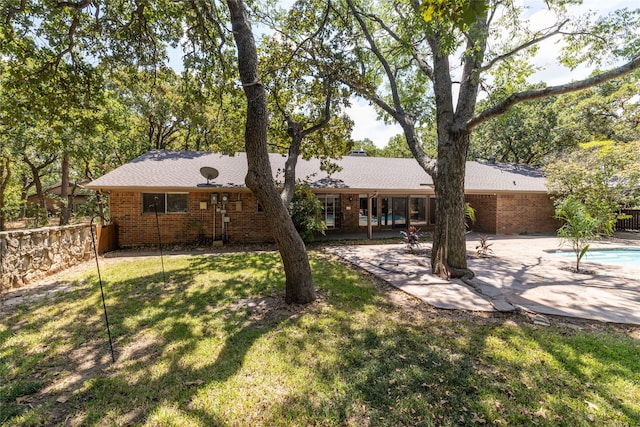 rear view of property with a fenced in pool, a yard, and a patio