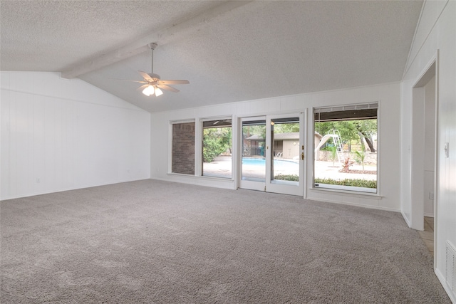 carpeted spare room featuring lofted ceiling with beams, a textured ceiling, a wealth of natural light, and ceiling fan